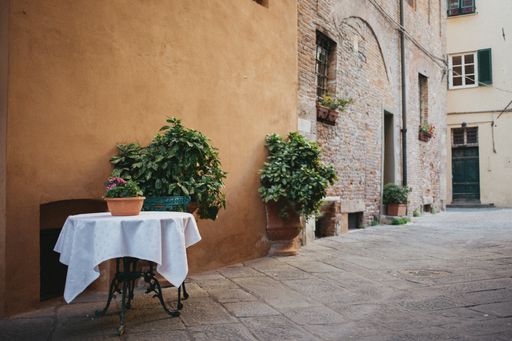 A small table with a chair at an outdoor cafe on an alley in Italy