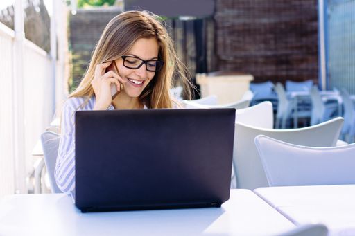 A landscape shot of a young female with glasses in a striped white and blue shirt working from home