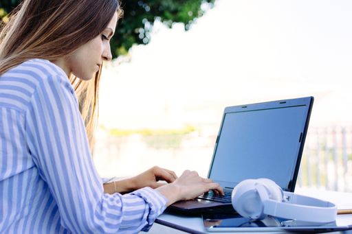 A landscape shot of a young female in a striped white and blue shirt working from home