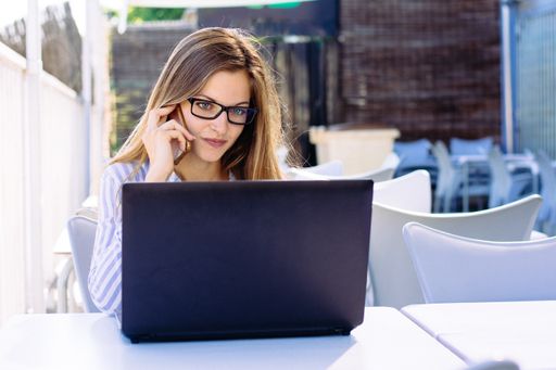 A landscape shot of a young female with glasses in a striped white and blue shirt working from home