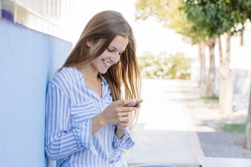 A landscape shot of a young female in a striped white and blue shirt holding a mobile phone