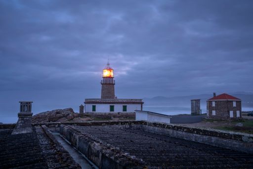 The Faro de Corrubedo lighthouse in Spain under a cloudy sky before the sunrise