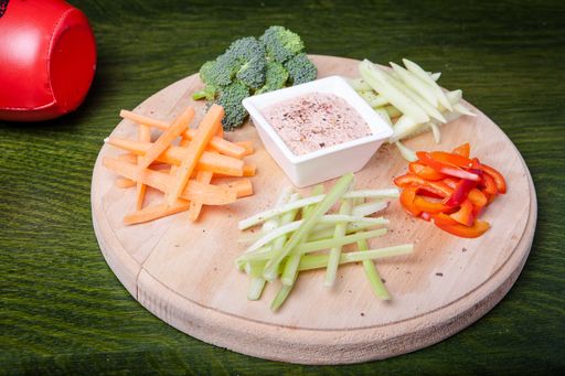 A beautiful closeup shot of vegetables with a sauce on a chopping board with green background