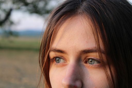A closeup shot of the beautiful eyes of a caucasian female looking away in a tree-covered field
