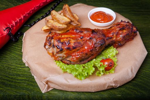 A closeup shot of pork steak with lettuce, fried potatoes, and ketchup with a green background