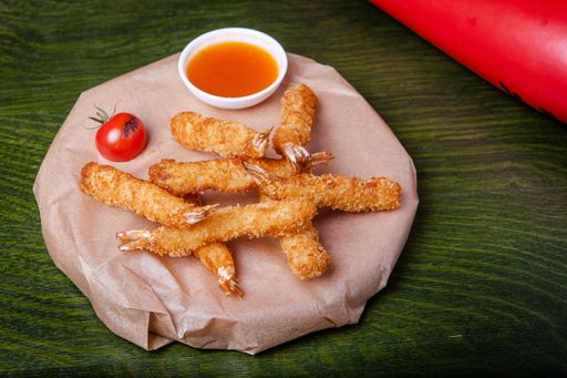 A closeup of chicken fries with sauce on a green background