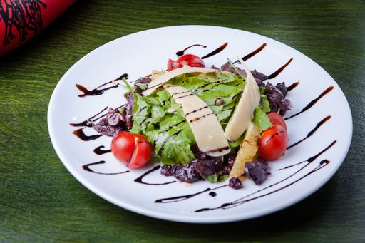 A closeup shot of decorated caesar salad in a white plate with a green background