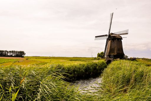 An old vintage windmill in Holland against a cloudy sky on a sunny day