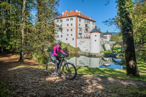 A woman riding a bicycle near the beautiful Sneznik castle in Sneznik, Slovenia