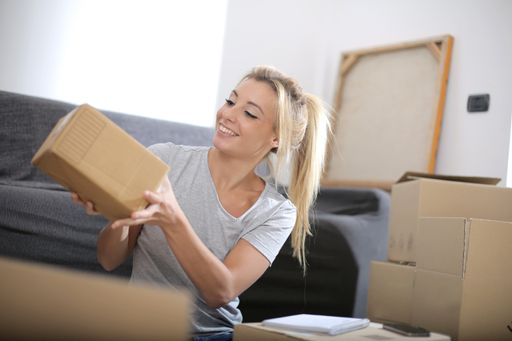 A view of a beautiful caucasian female receiving a cardboard box, surrounded with boxes