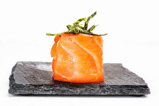 A closeup shot of a sushi roll on a black stone plate