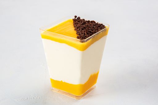 A closeup shot of passion fruit dessert with grated chocolate on the top, served in a small plastic cup