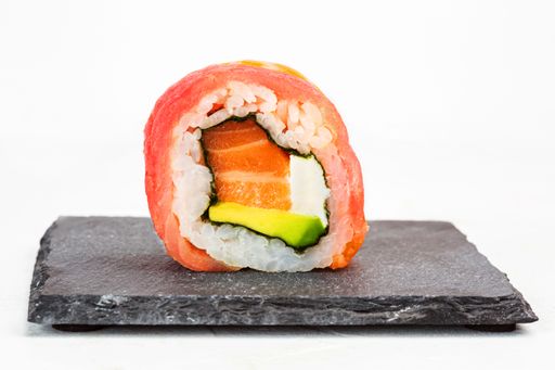 A closeup shot of a sushi roll on a black stone plate
