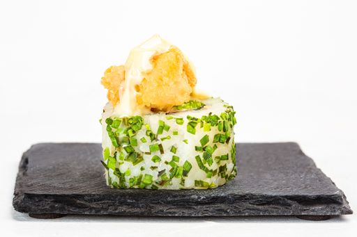 A closeup shot of a sushi roll on a black stone plate