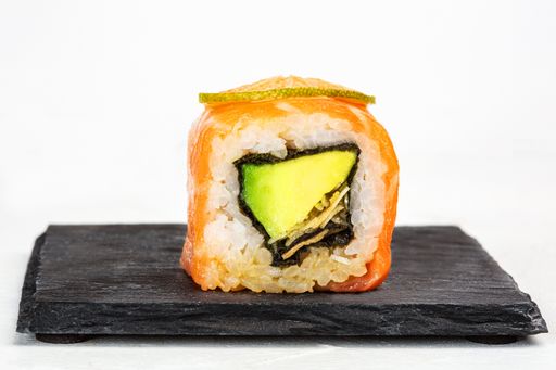 A closeup shot of delicious sushi roll with avocado on white background