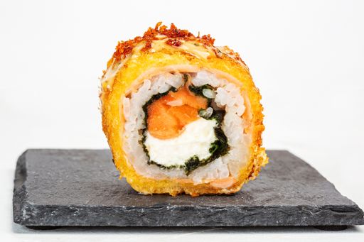 A closeup shot of a sushi roll on a black stone plate