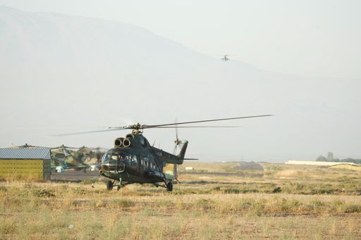 A wide shot of a military helicopter getting ready to take off in a large desert field