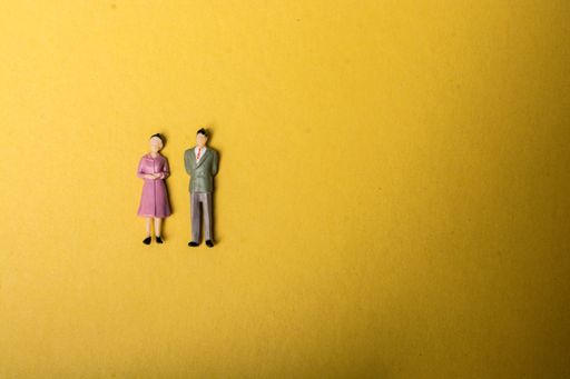 A high angle shot of a male and female toy on a yellow surface