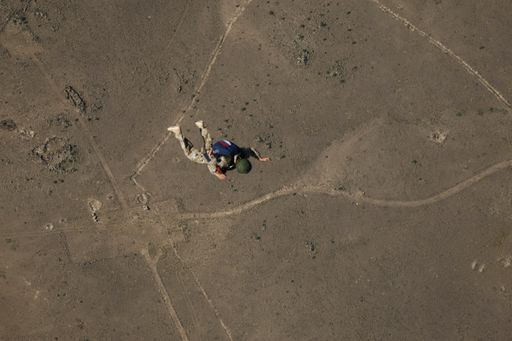 An aerial shot of a paratrooper flying towards the ground in the air