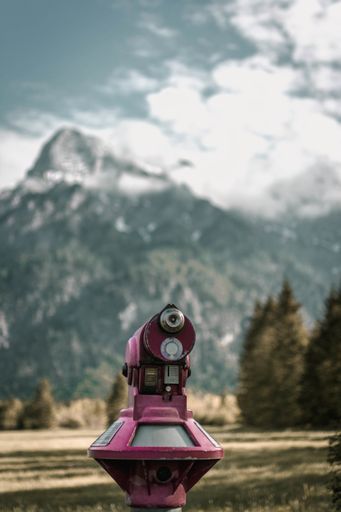 A vertical shot of a pink tower viewer surrounded by mountains and trees under the sunlight