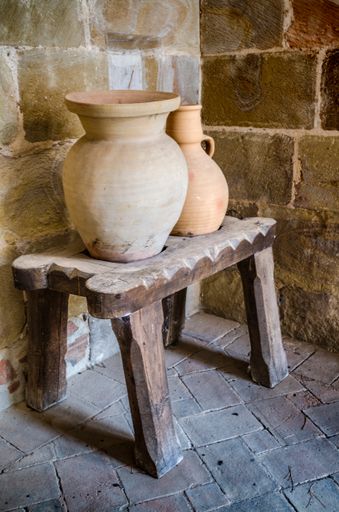 A vertical shot of ceramic jugs on a wooden table against the brick wall