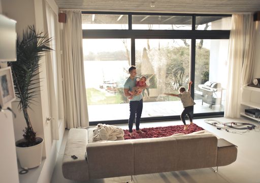 A young happy father playing with two children in an apartment under the sunlight