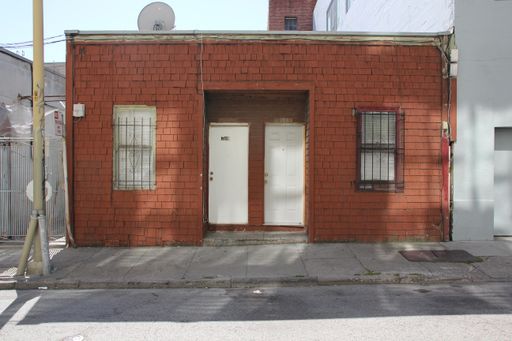 A beautiful exterior of an old traditional house with red brick walls and two small white doors