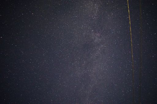 A breathtaking shot of the beautiful starry sky in the countryside with a telephone wire on the side