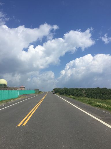 A beautiful view of a road surrounded by fields under a cloudy sky