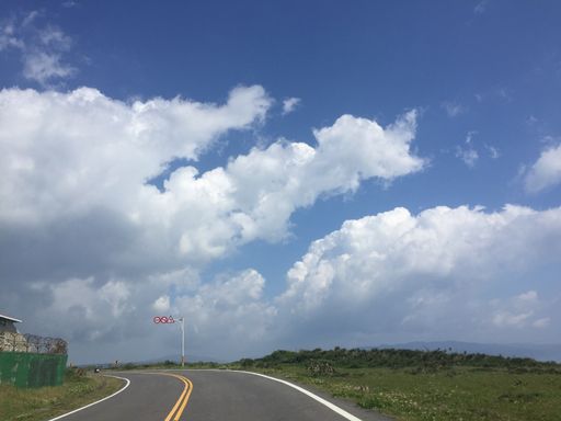 A beautiful view of a road surrounded by fields under a cloudy sky