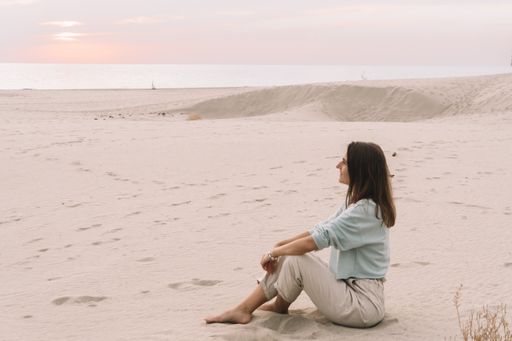 A Caucasian woman traveler enjoying the view seating on sand dunes