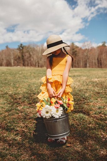 A closeup of a girl in yellow dress holding flowers