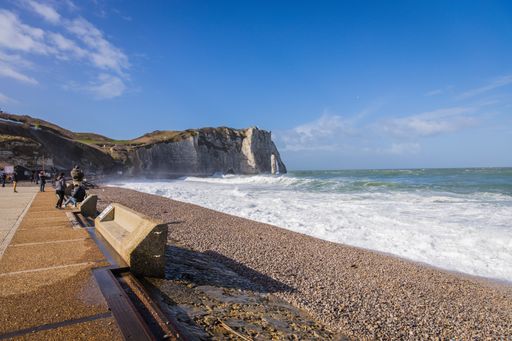 The cliffs of Etretat in France and a wavy sea under a blue cloudy sky on a sunny day