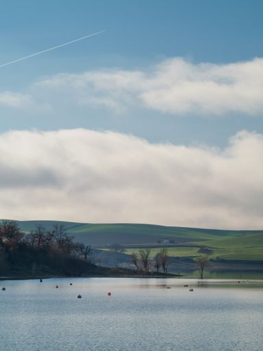 A beautiful view of a lake with a hills and sky background