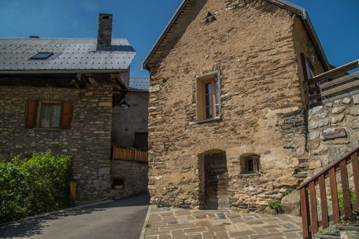 A scenic view of antique stone buildings surrounded by green mountains in Isere, France