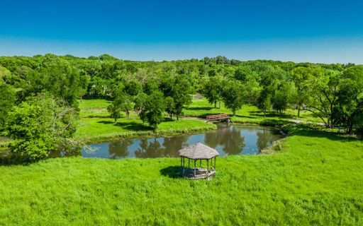 A beautiful view of a small lake among bright green field and forest