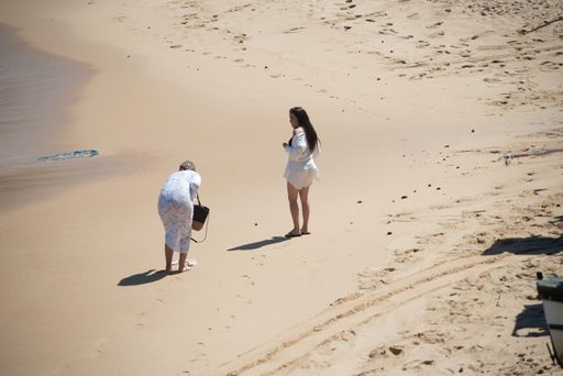 Two women walking on the sands of the famous Rio Vermelho beach in the city of Salvador, Bahia, Brazil