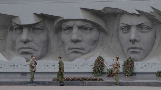 Teenage soldiers in front of a monument to World War II