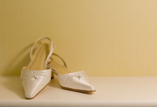 A closeup shot of white silk wedding shoes on shelf