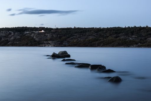 A beautiful view of a lake with huge rocks under the blue sky