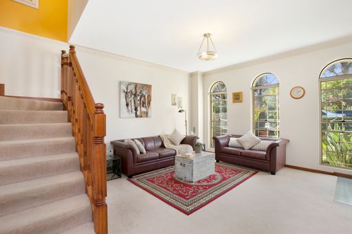 A living room interior with brown leather furniture and wooden stairs