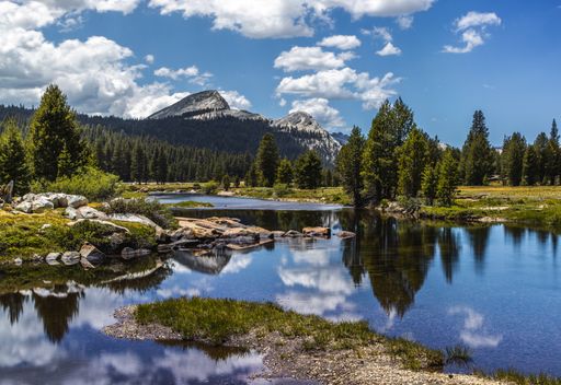A scenic view of a calm lake with reflection of forest and mountain landscape on the surface