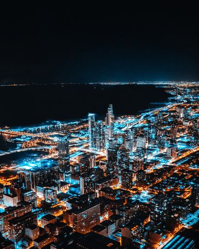 A vertical aerial shot of skyscrapers in the city lights during nighttime