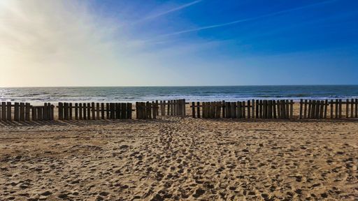 A scenic view of wooden fence on the shore on a bright day