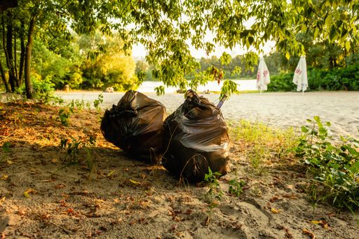 A closeup of full trash bags on the beach