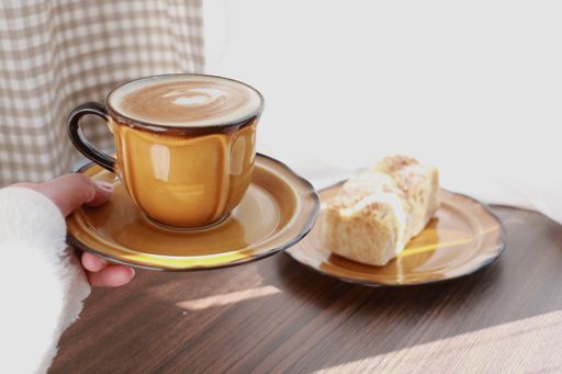 A closeup shot of a cup of coffee with pie on a table