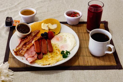A breakfast containing omelet, sausage pancakes a cup of coffee and juice