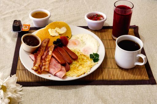 A breakfast containing omelet, sausage pancakes, a cup of coffee and juice