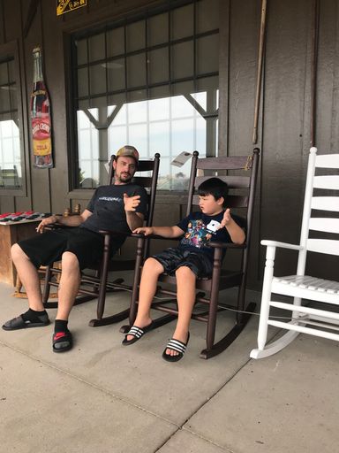 A relaxing view of a father and son talking on porch in rocking chair in Tulsa, USA