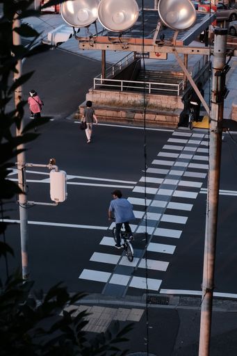 A vertical shot of people, two of them riding bicycles, crossing the street